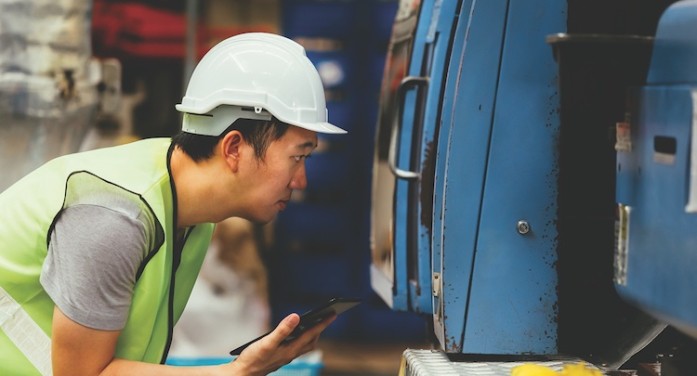 man in hardboard in manufacturing plant inspecting machinery